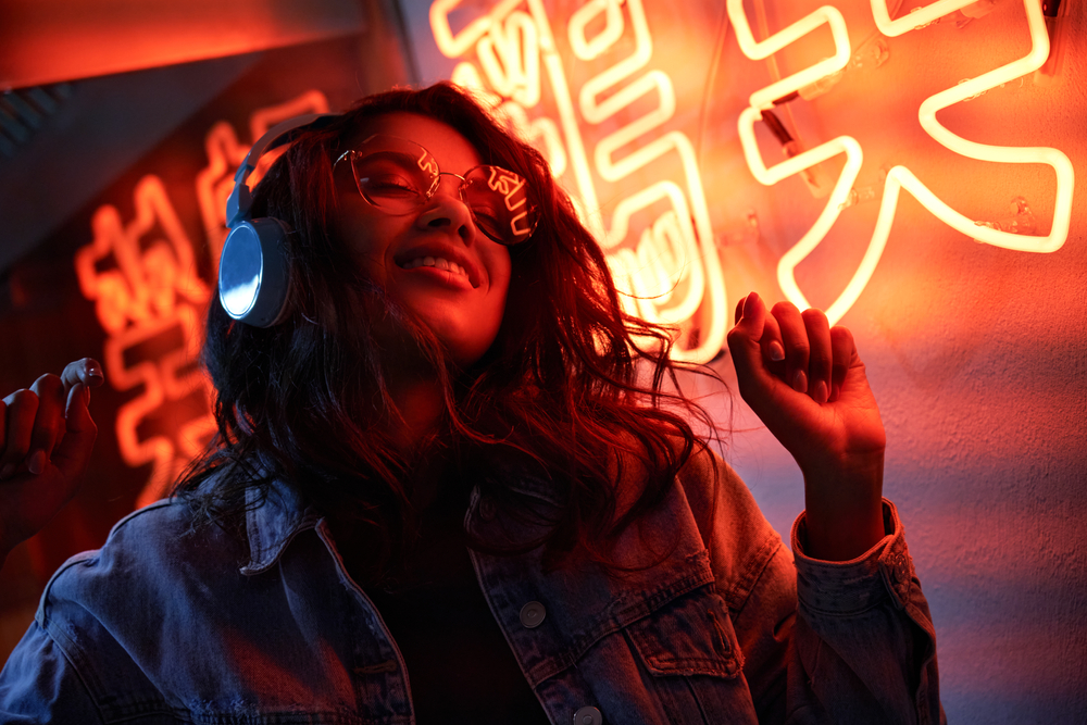 A woman wearing glasses is illuminated by red neon lights in a dimly lit space - Eye Doctor in Jewett City, CT A woman wearing glasses is illuminated by red neon lights in a dimly lit space - Eye Doctor in Jewett City, CT